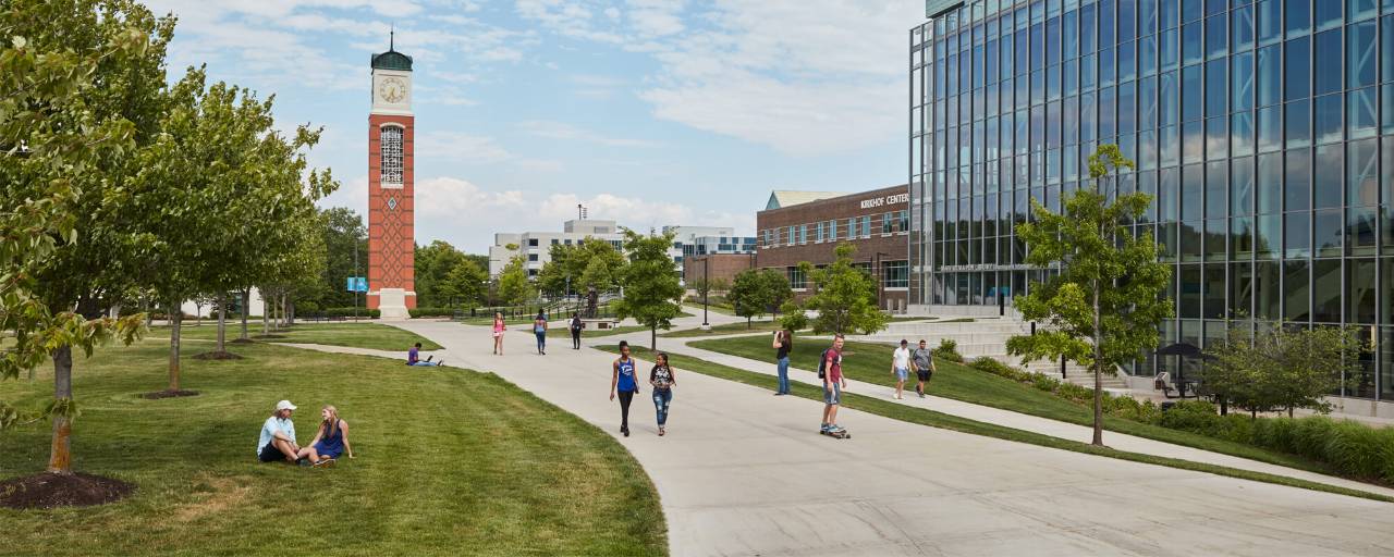Students walking through campus with the Kirkhof Center and clock tower in the background